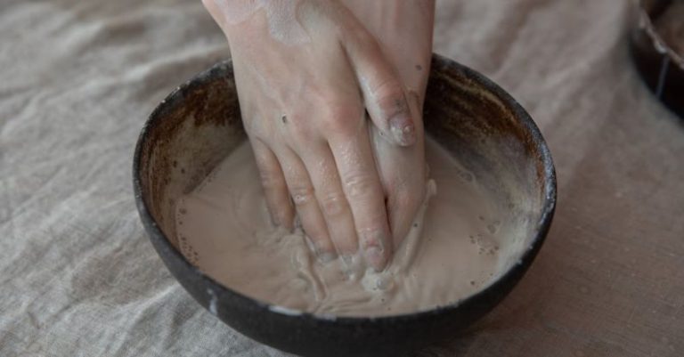 Consistency - From above of crop anonymous craftsperson mixing clay in round shaped bowl in workroom