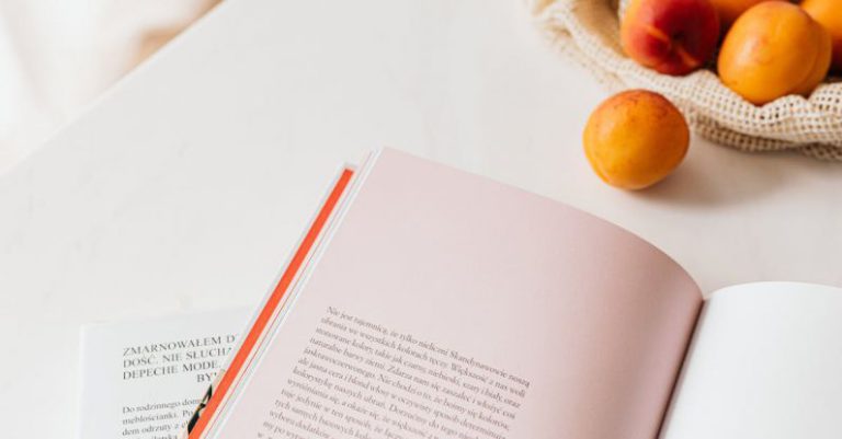 Product Pages - From above of opened book placed on white table near cotton sack with natural ripe apricots