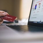 E-Commerce - Black and Gray Laptop Computer With Turned-on Screen Beside Person Holding Red Smart Card in Selective-focus Photography