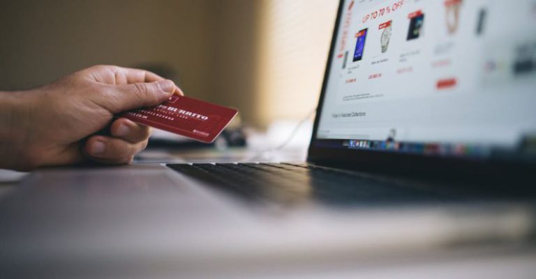 E-Commerce - Black and Gray Laptop Computer With Turned-on Screen Beside Person Holding Red Smart Card in Selective-focus Photography